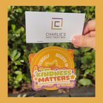 Hand holding a clear treat box with 'Charlie's Safe Treat Box' branding and a colorful design with text.