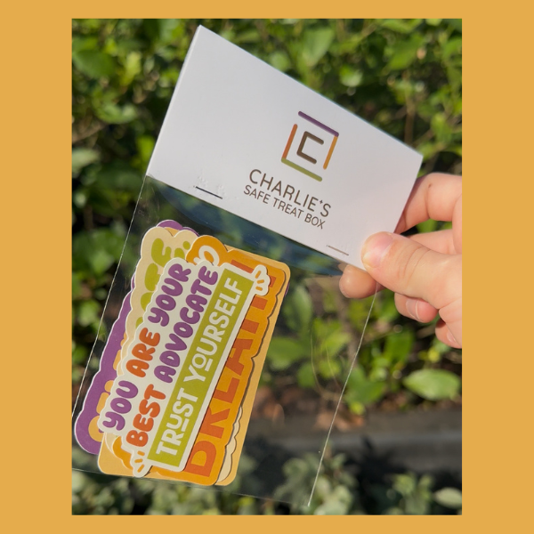 Hand holding a card with a motivational message and 'Charlie's Safe Treat Box' branding.