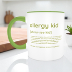 White mug with green handle featuring text about 'allergy kid' on a kitchen counter.