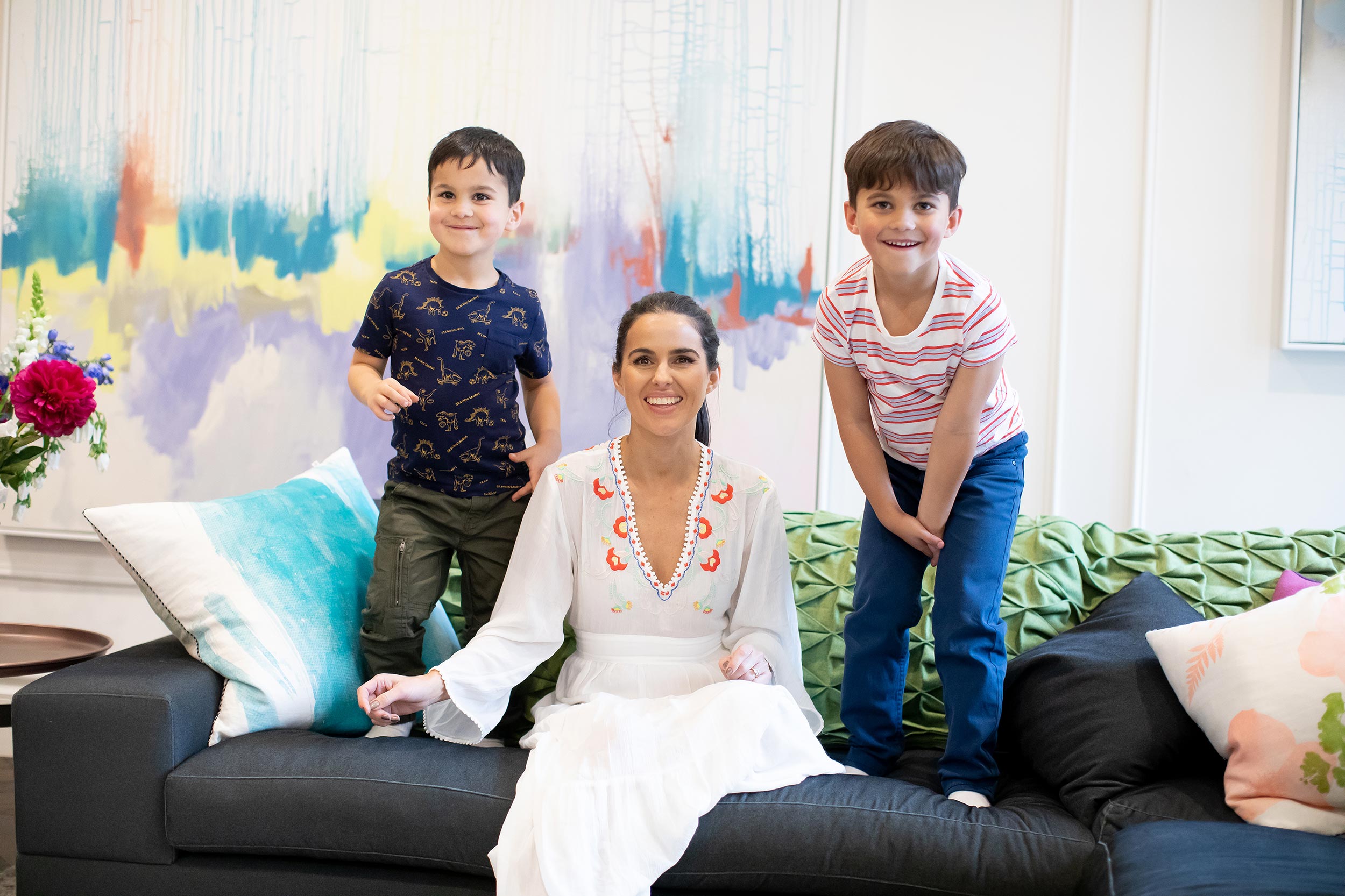 Woman sitting on a couch with two children in a living room setting