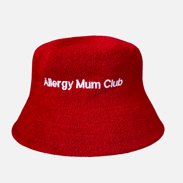 Red bucket hat with 'Allergy Mum Club' text on a light gray background