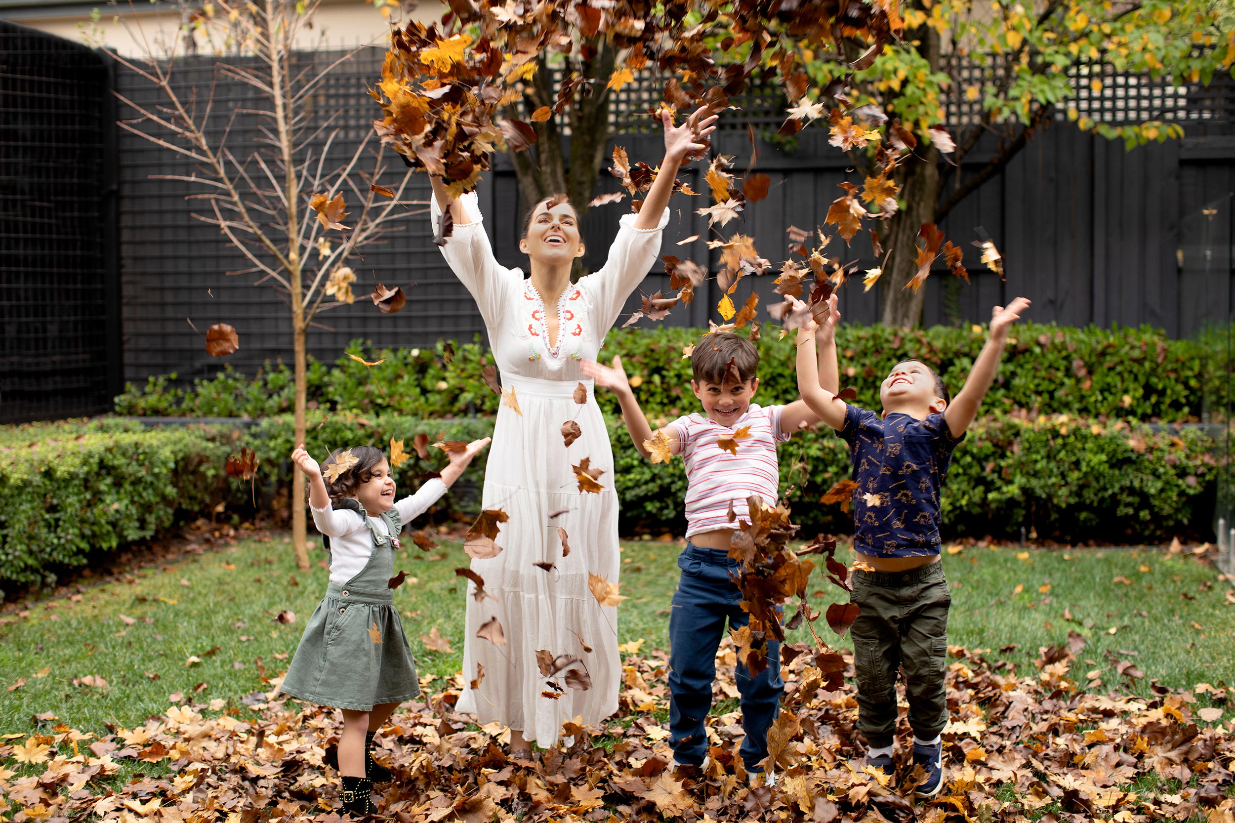 Woman and children playing with leaves in a garden