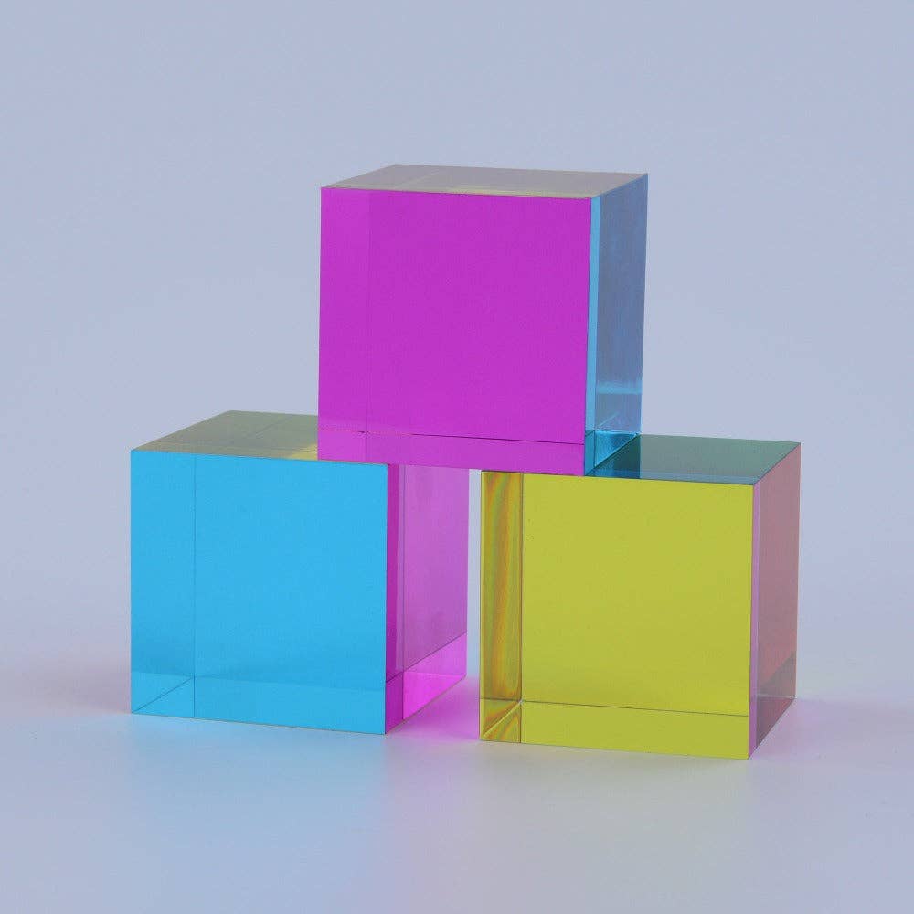 Three colored cubes (pink, blue, yellow) stacked on a light gray background