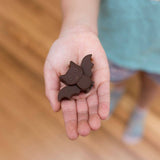 Chocolate bat-shaped cookie held in a child's hand on a wooden floor.