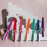 Colorful knives in a white stand on a light pink background