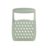 A sage green silicone kitchen grater with a handle, shown against a plain white background.