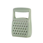 A sage green plastic cheese grater with a built-in handle, shown on a plain white background.