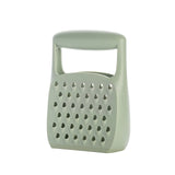 A sage green plastic cheese grater with a built-in handle, shown on a plain white background.