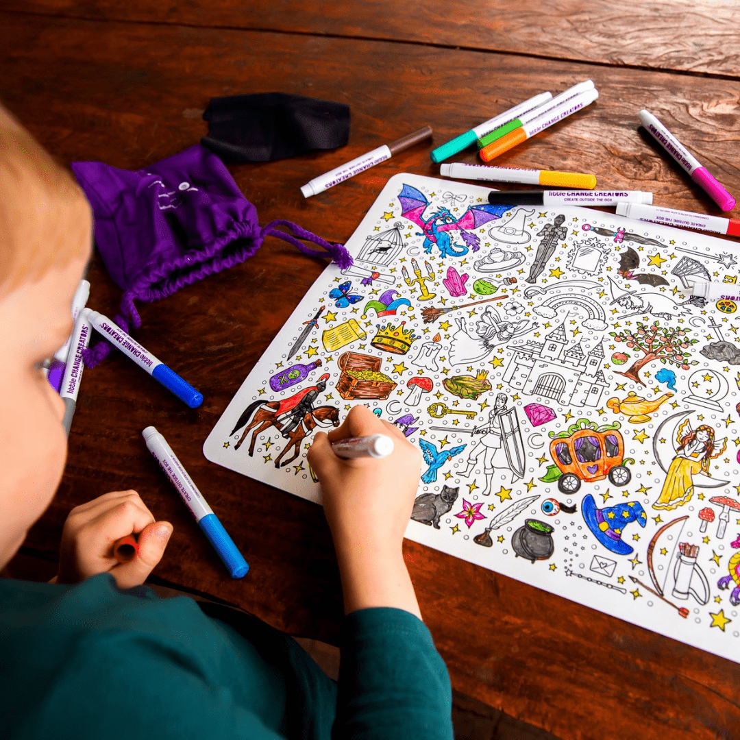 Child coloring a sheet of stickers on a wooden table with markers.