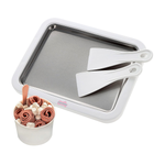 Baking tray with spatulas and a cup of ice cream on a white background