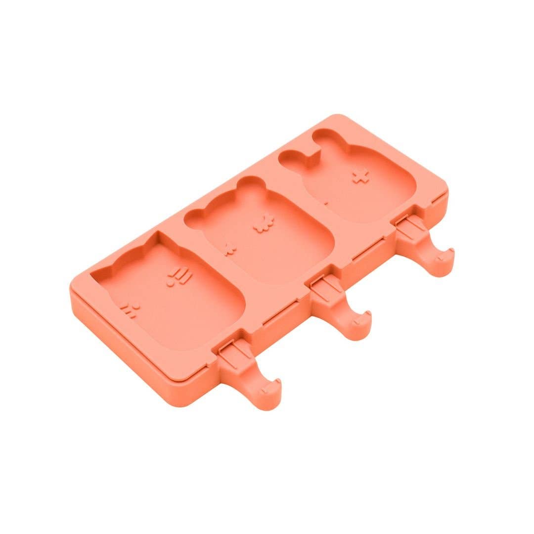 Coral-colored ice cream mold with bear and square shapes on a white background